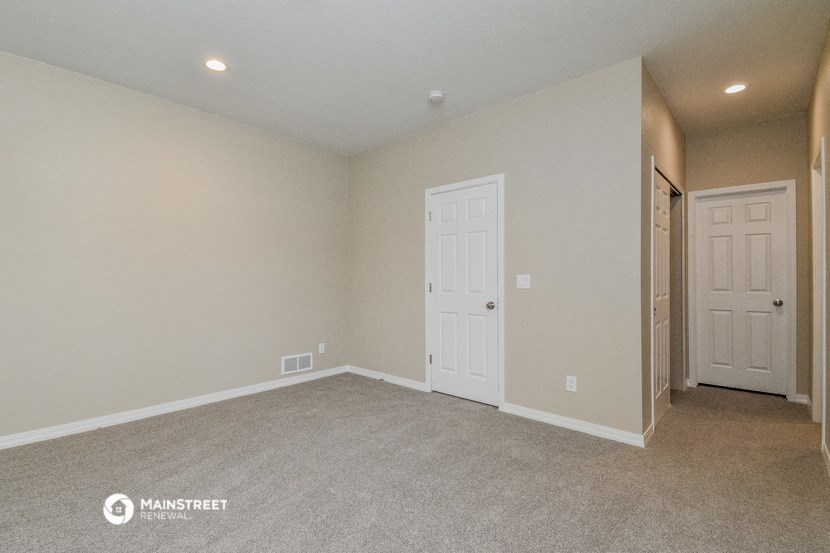 an empty living room with two doors and a door to a closet