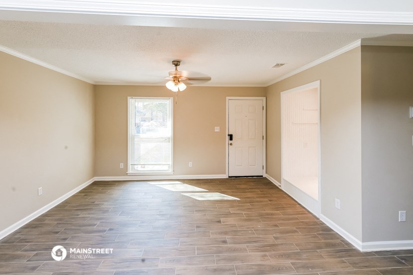 the spacious living room with wood floors and a ceiling fan