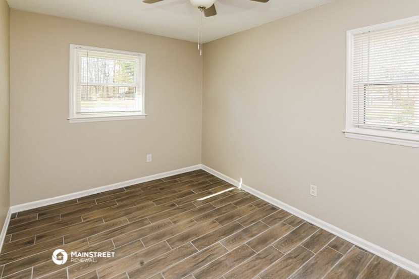 the spacious living room with wood flooring and two windows
