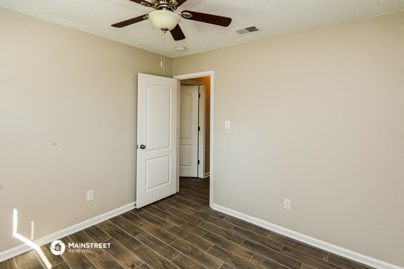 a bedroom with a ceiling fan and a door to a closet