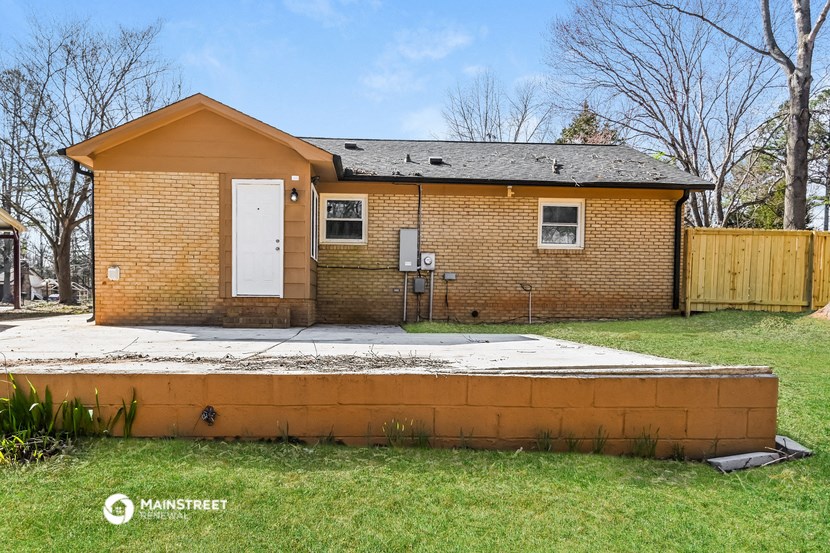 a small brick house with a sidewalk in front of it