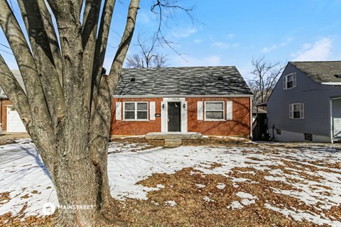 a brick house with a large tree in front of it