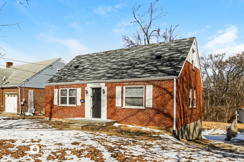 a small brick house with a gray roof and a gray porch