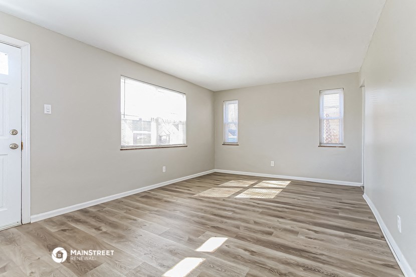 an empty living room with wood flooring and a window