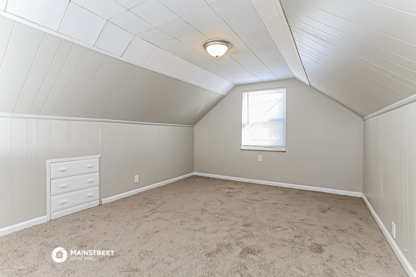 the attic of a house with white walls and a window