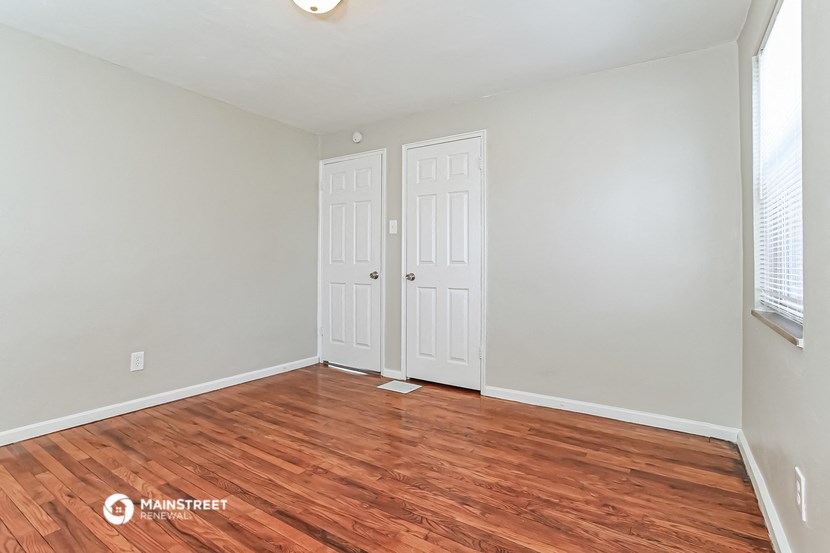 the living room of an apartment with wood flooring and two closets