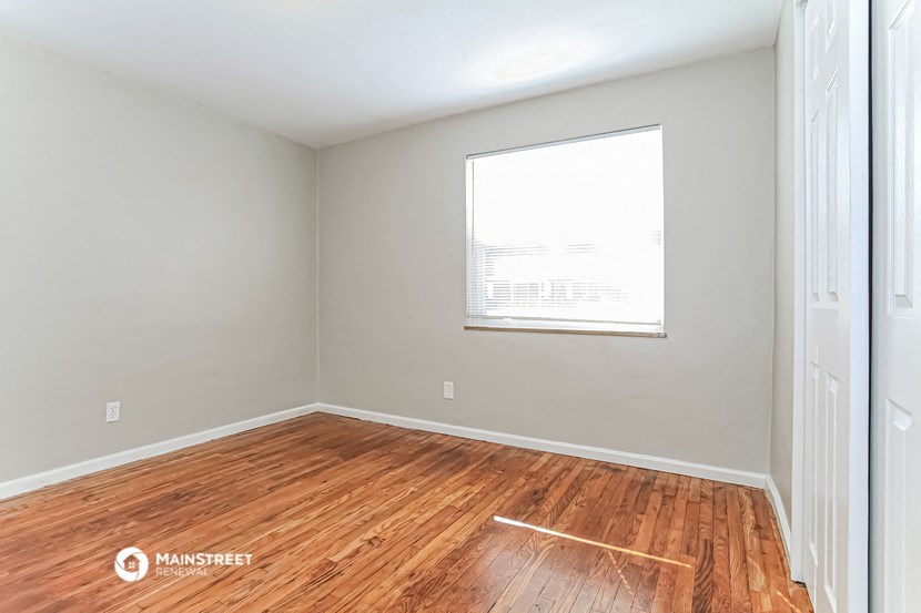 an empty room with wood floors and a window