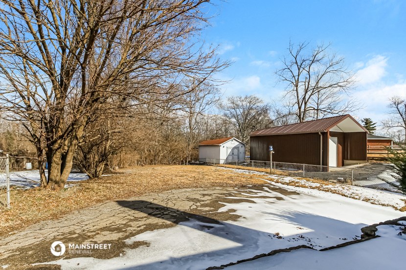 a house with a barn and a driveway in the snow