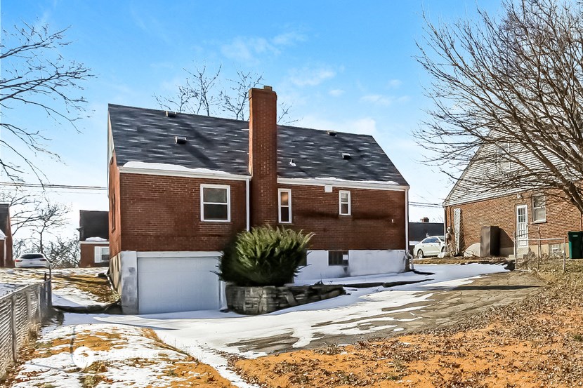 a red brick house with a black roof and snow on the ground