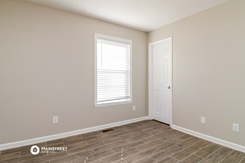 the spacious living room with wood flooring and a white door