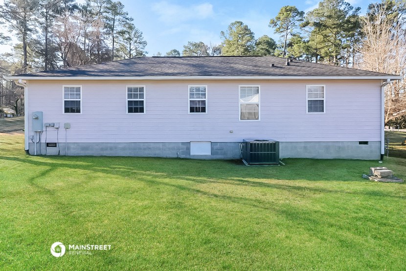 a white house with a grass yard and a trash can