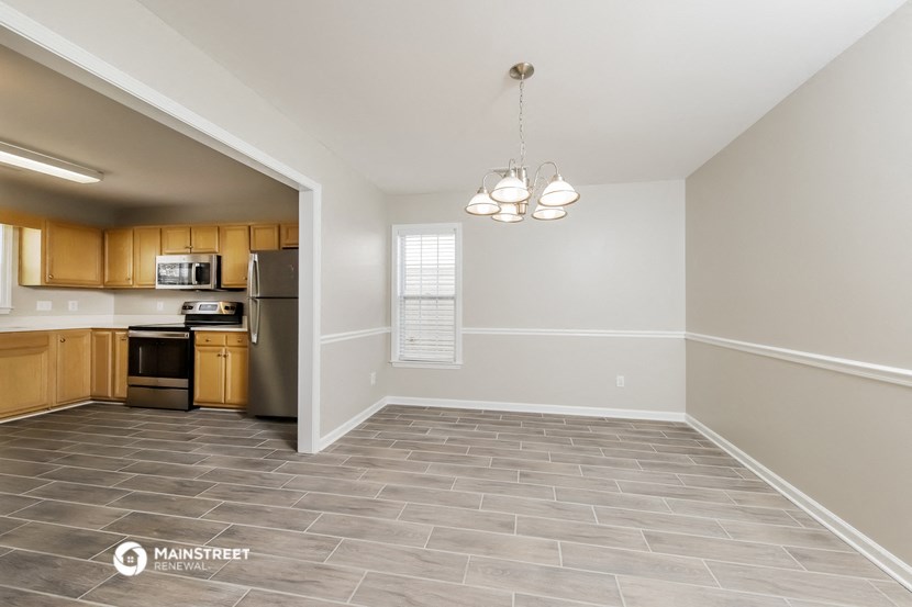 an empty living room and kitchen with a refrigerator and microwave