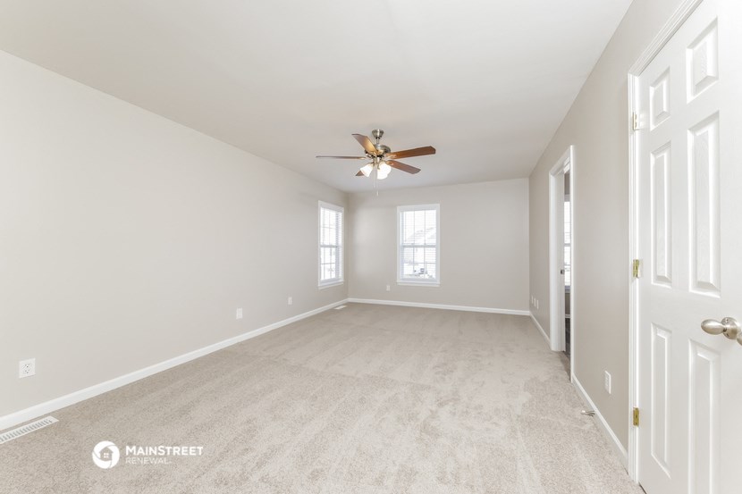 an empty living room with a ceiling fan