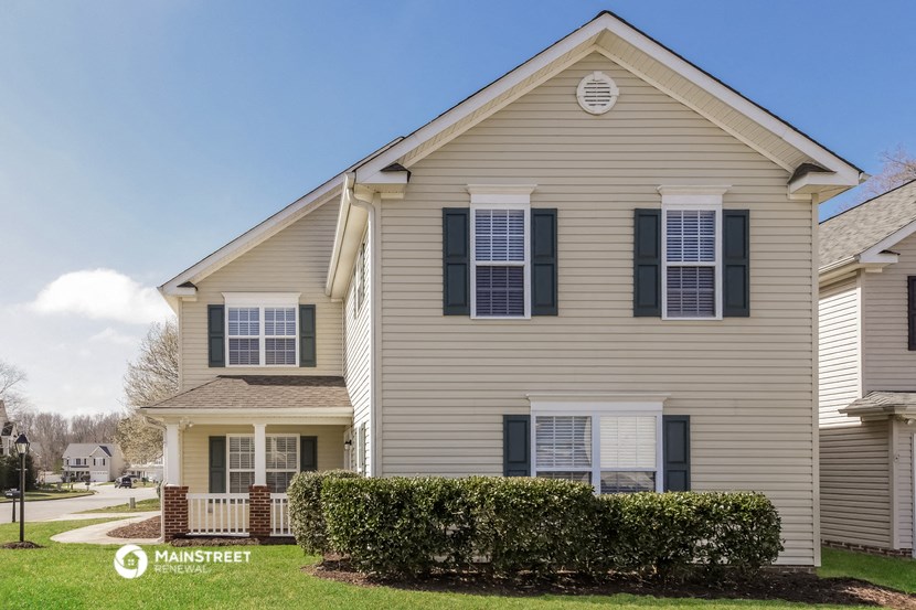 a beige house with bushes in front of it