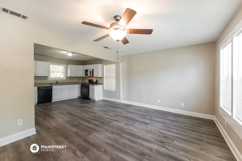 an empty living room and kitchen with a ceiling fan