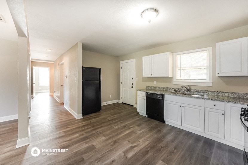 an empty kitchen with white cabinets and a black refrigerator