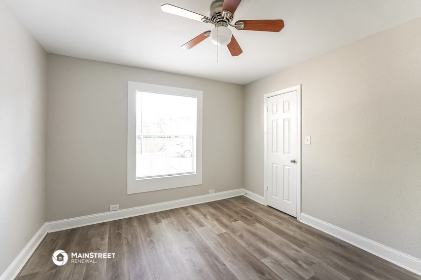 an empty room with a ceiling fan and a window