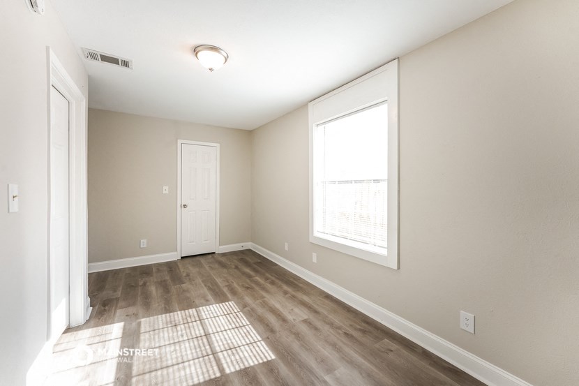 the spacious living room with a large window and wood flooring