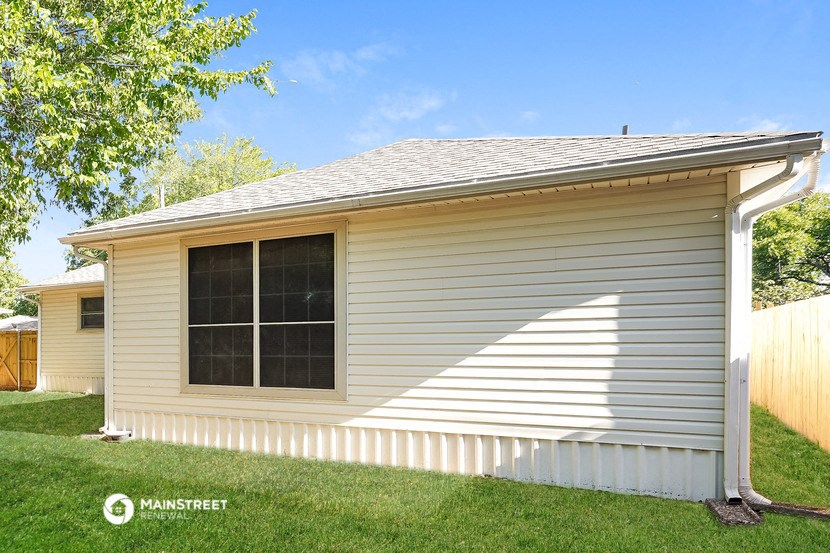the front of a white house with a white fence and grass