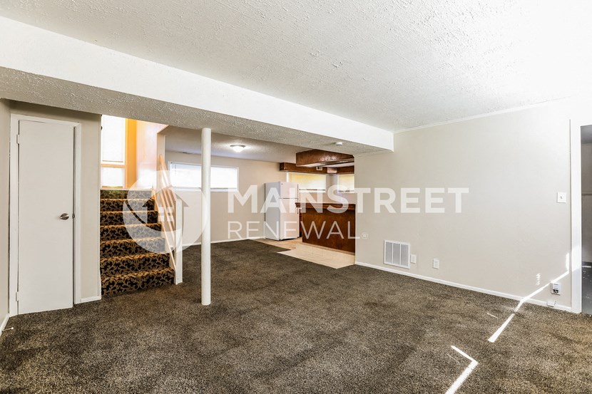 a renovated living room with a carpeted floor and a staircase