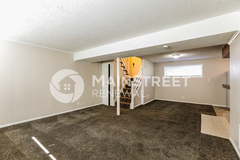 a living room with a carpeted floor and a staircase