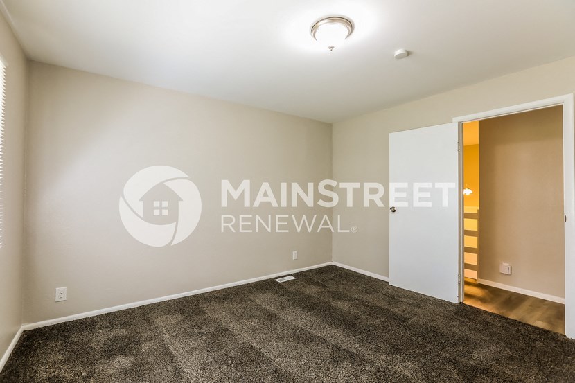 a living room with carpet and a door to a hallway