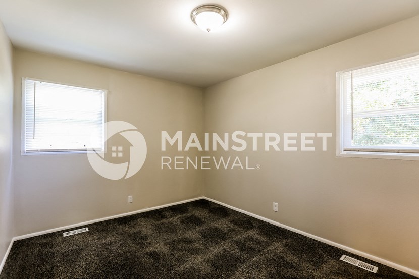 a bedroom with carpet and two windows