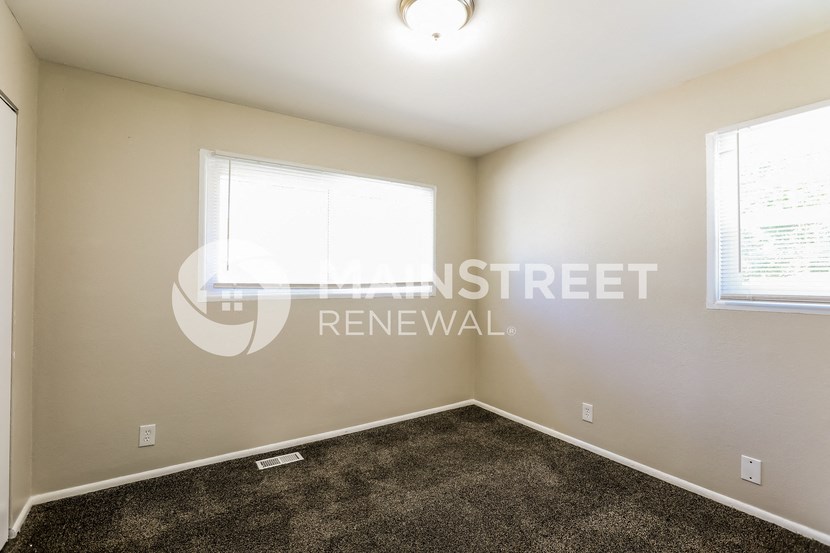a bedroom with carpet and two windows