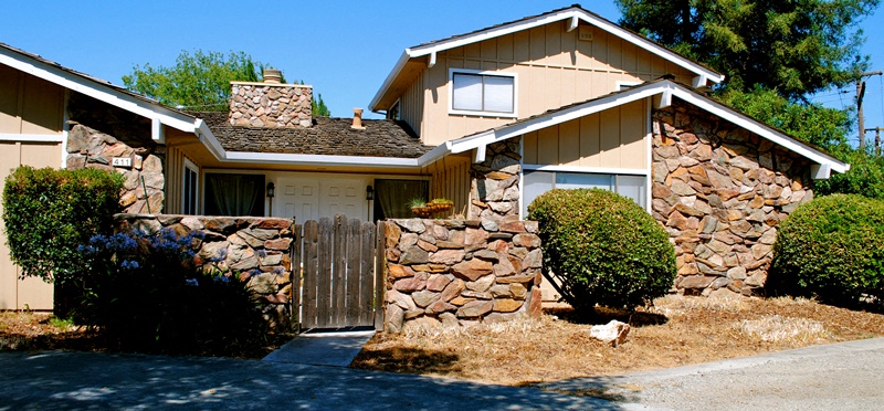 a house with a fence and a stone wall