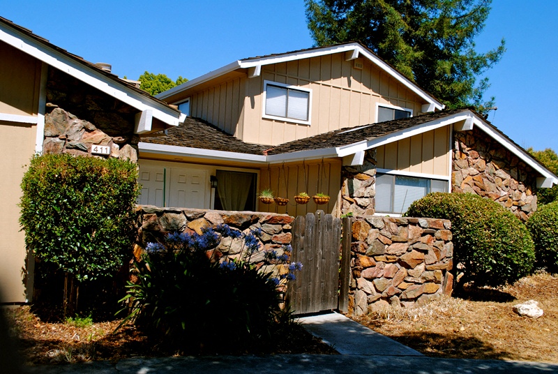 a house with a stone wall and a wooden gate