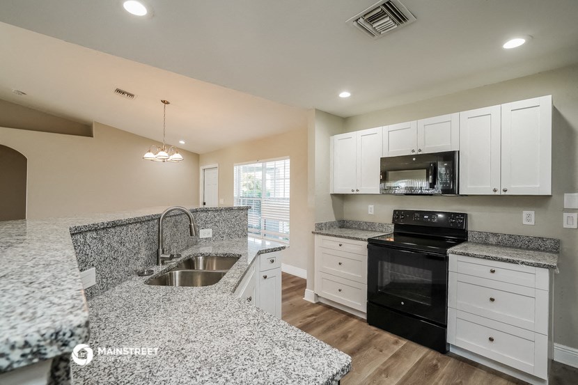 an open kitchen with granite counter tops and black appliances
