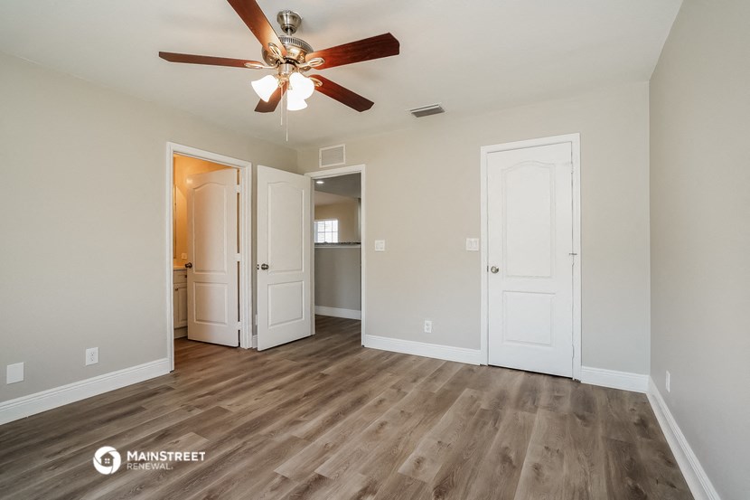 a living room with a ceiling fan and a door to a kitchen