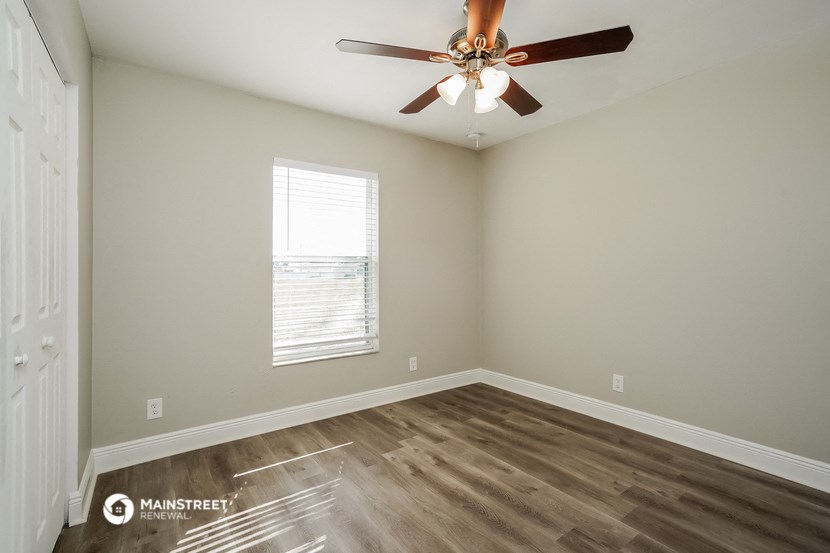 an empty room with a ceiling fan and a window
