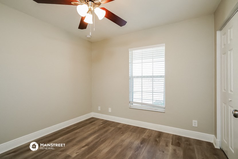 the spacious living room with a ceiling fan and wood flooring