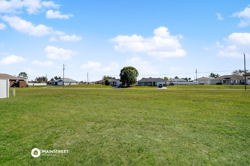 a large grass field with houses in the background