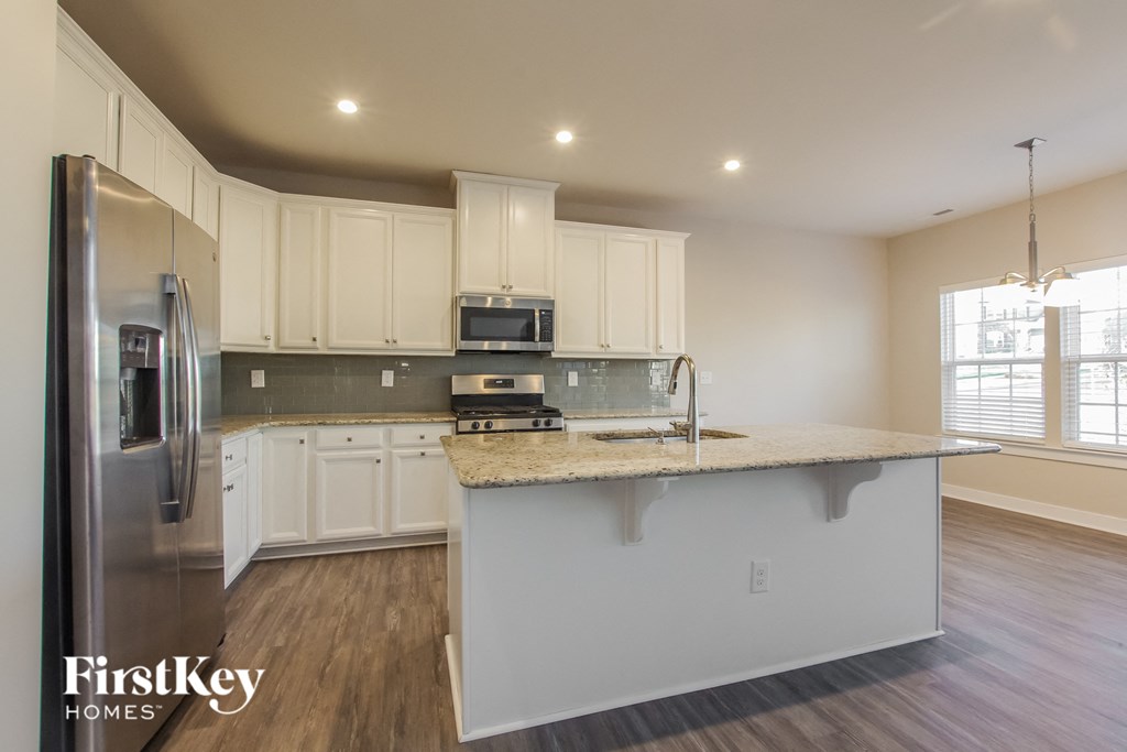 a kitchen with white cabinets and a marble counter top