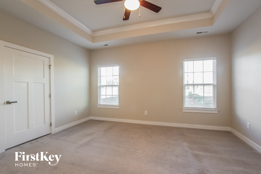 an empty room with a ceiling fan and two windows
