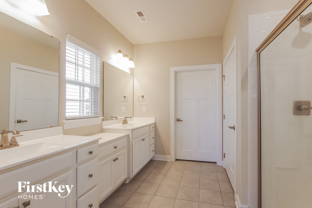 a bathroom with two sinks and a mirror and a shower