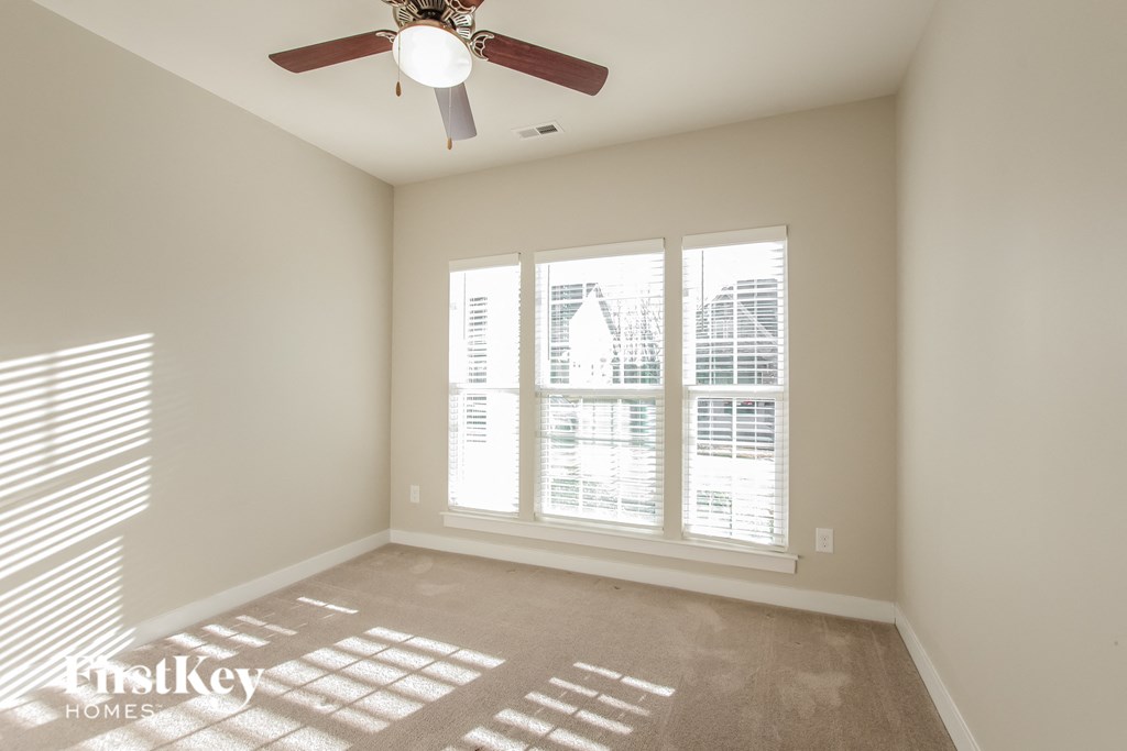 a living room with a ceiling fan and large windows