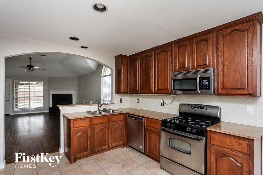 A kitchen with wooden cabinets and a stove top oven.