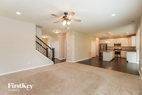A spacious living room with a staircase and a kitchen in the background.