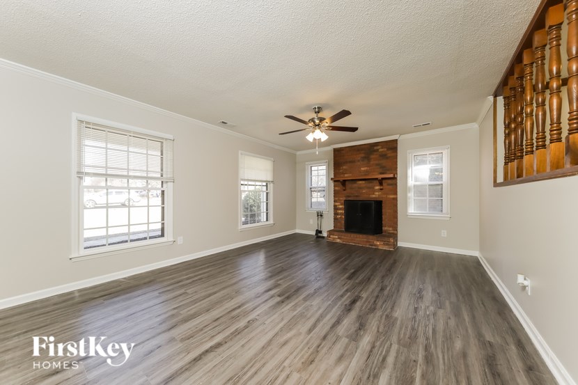 A spacious room with wooden floors and a fireplace.