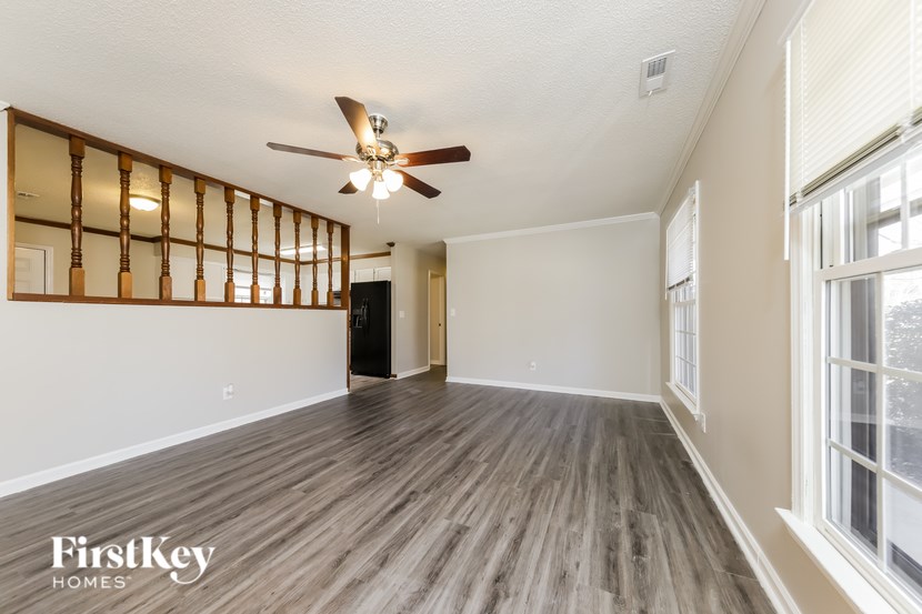 A spacious room with wooden flooring and a ceiling fan.
