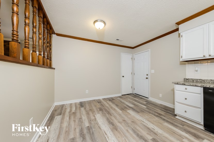 A kitchen with a wood floor and white cabinets.