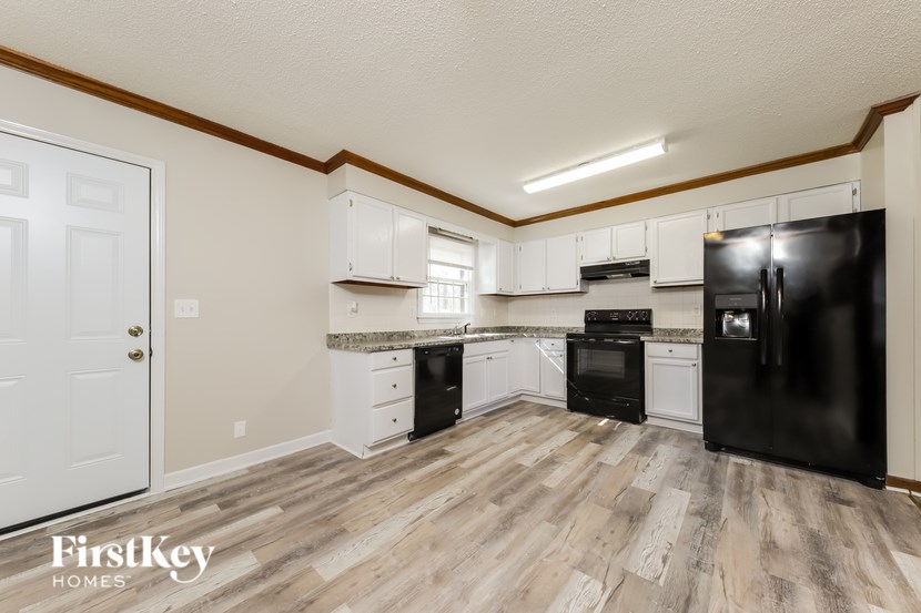 A kitchen with black appliances and wooden floors.
