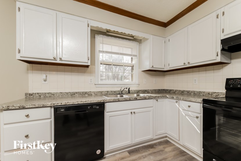 A kitchen with white cabinets and a granite countertop.