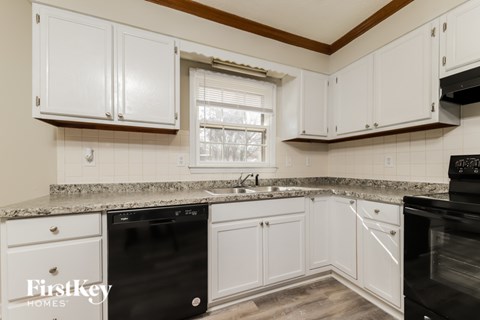 A kitchen with white cabinets and a granite countertop.