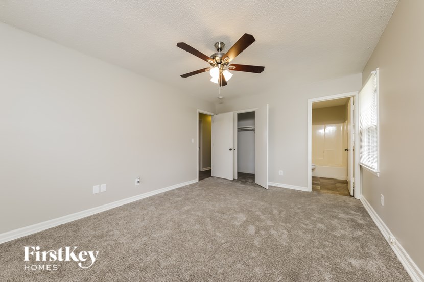 A spacious room with a ceiling fan and carpeted floor.