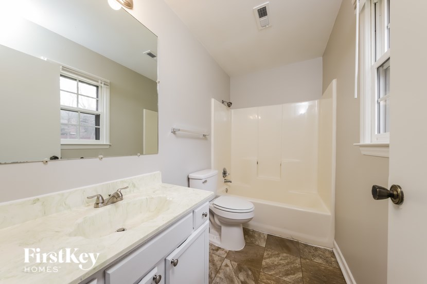 A bathroom with a marble countertop and white fixtures.