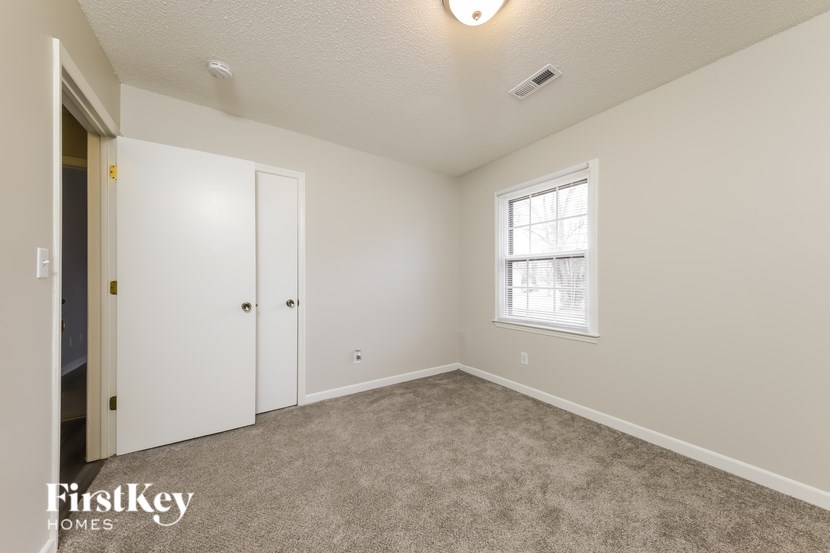 A white door and a window with a white frame in a room with a carpet floor.